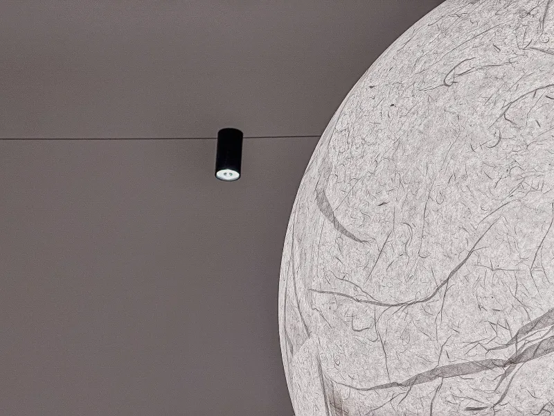 Un piccolo faretto a soffitto accanto a una grande sfera di carta illuminata